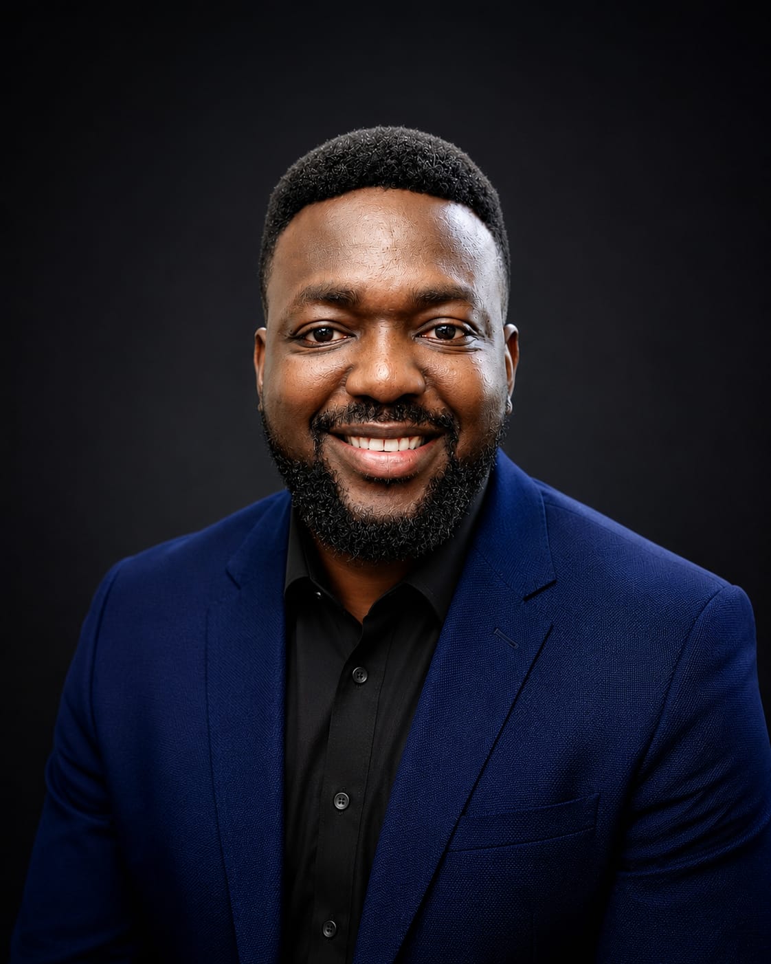 Alex Olerimi smiling in a blue blazer